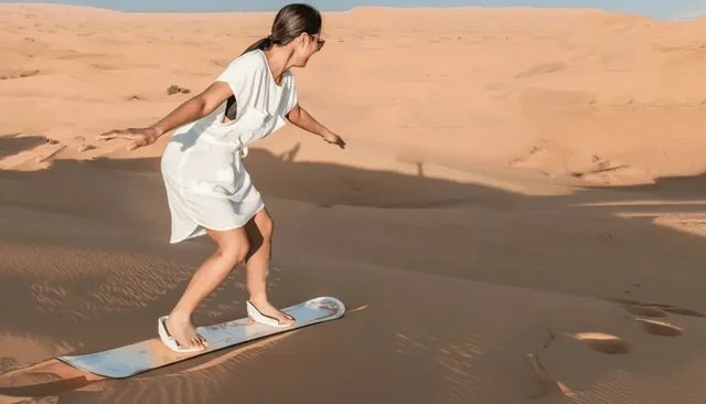 A sandboarder descending a dune