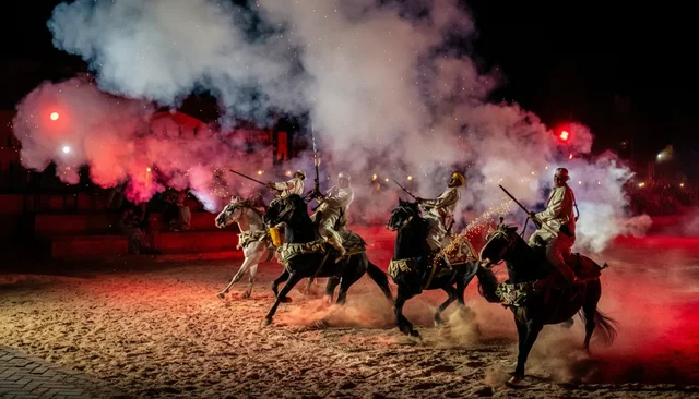 Horse riders performing in an illuminated evening arena